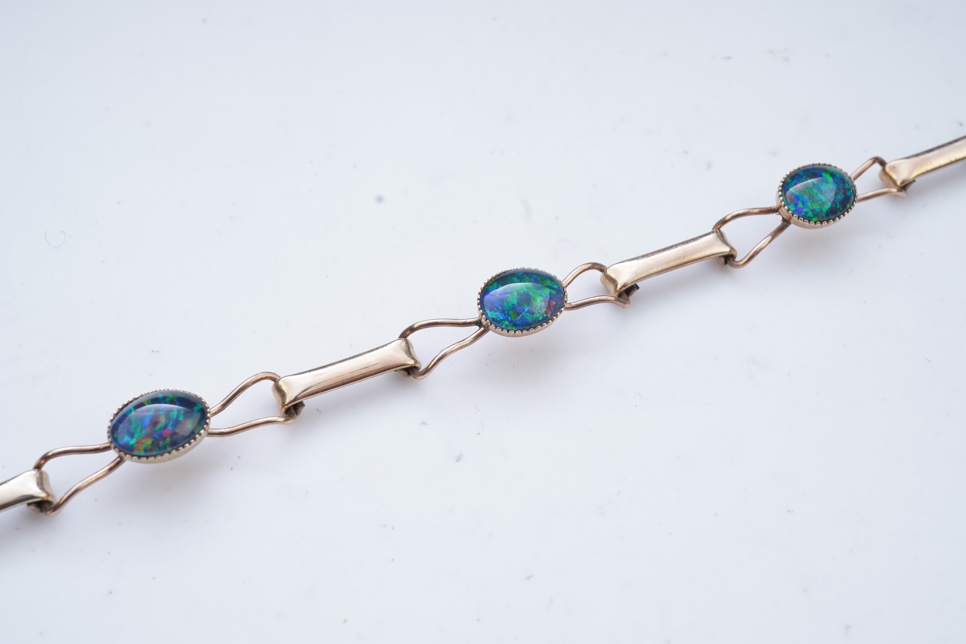 An opal triplet bracelet and pair of earrings, comprising: a gold bracelet set with opal triplets, length 18cm; and a pair of studs set with opal doublets, mounted in gold, length 0.8cm each, post fittings, stamped 585,